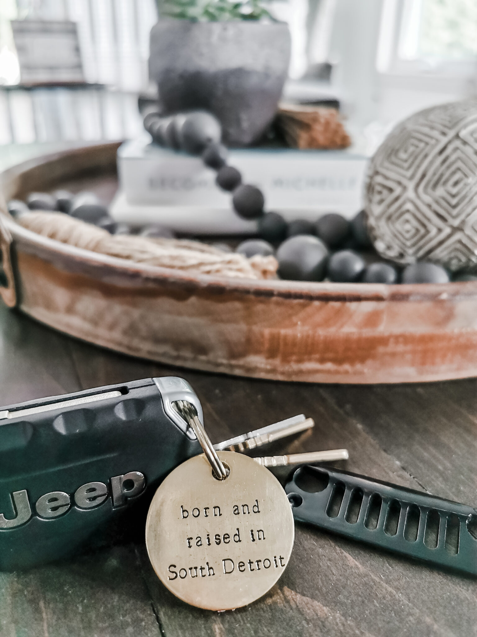 Close of Jeep keys on a table. There is a keychain that says, "Born in Raised in South Detroit."