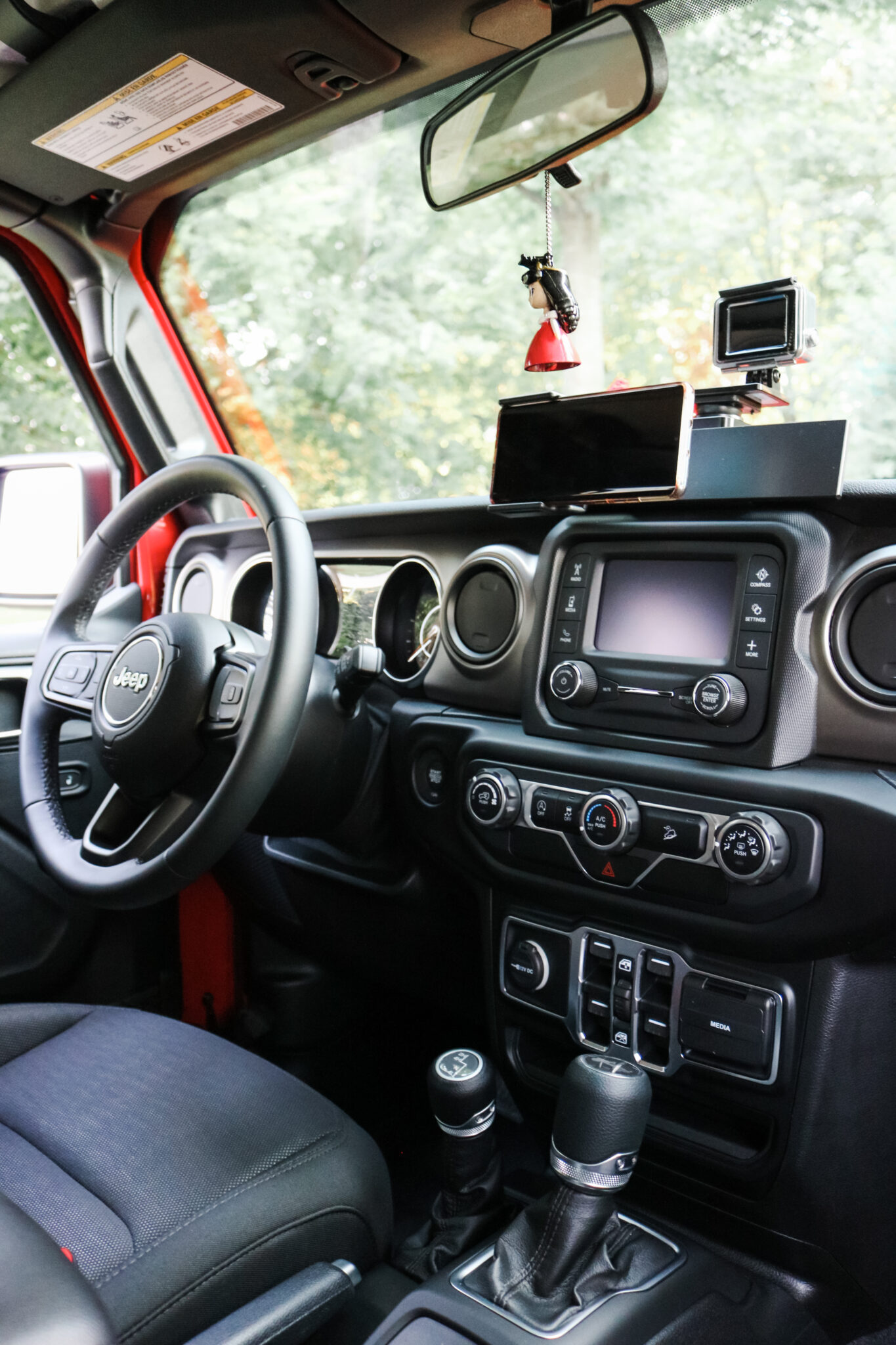 An interior view of the inside of the Jeep 2020. It's equipped with ProClip USA Jeep Accessories. A Center Dash Mount, standard phone holder, and a GoPro adapter.