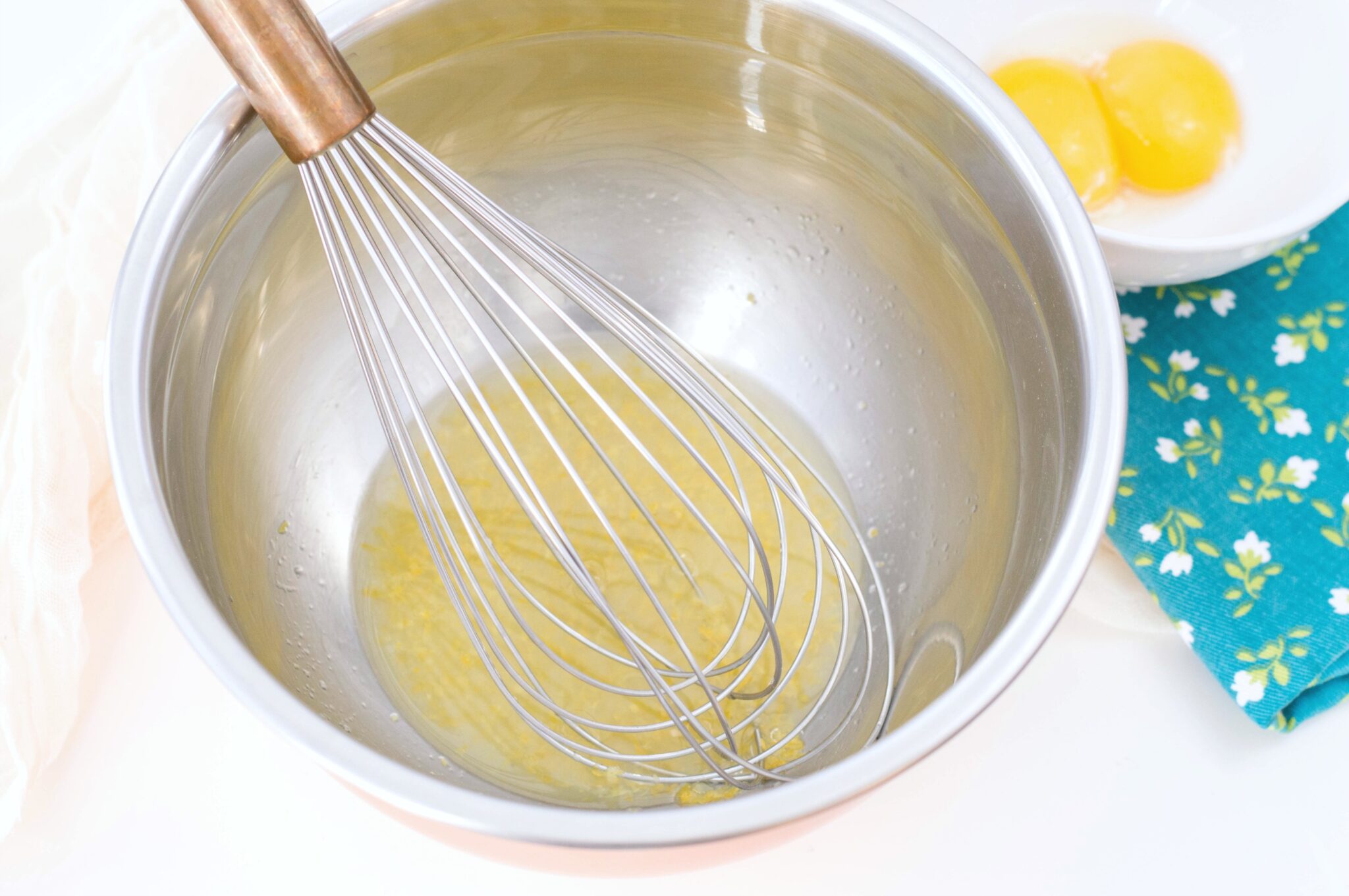 A bowl with a whisk mixing lemon juice and lemon rind.