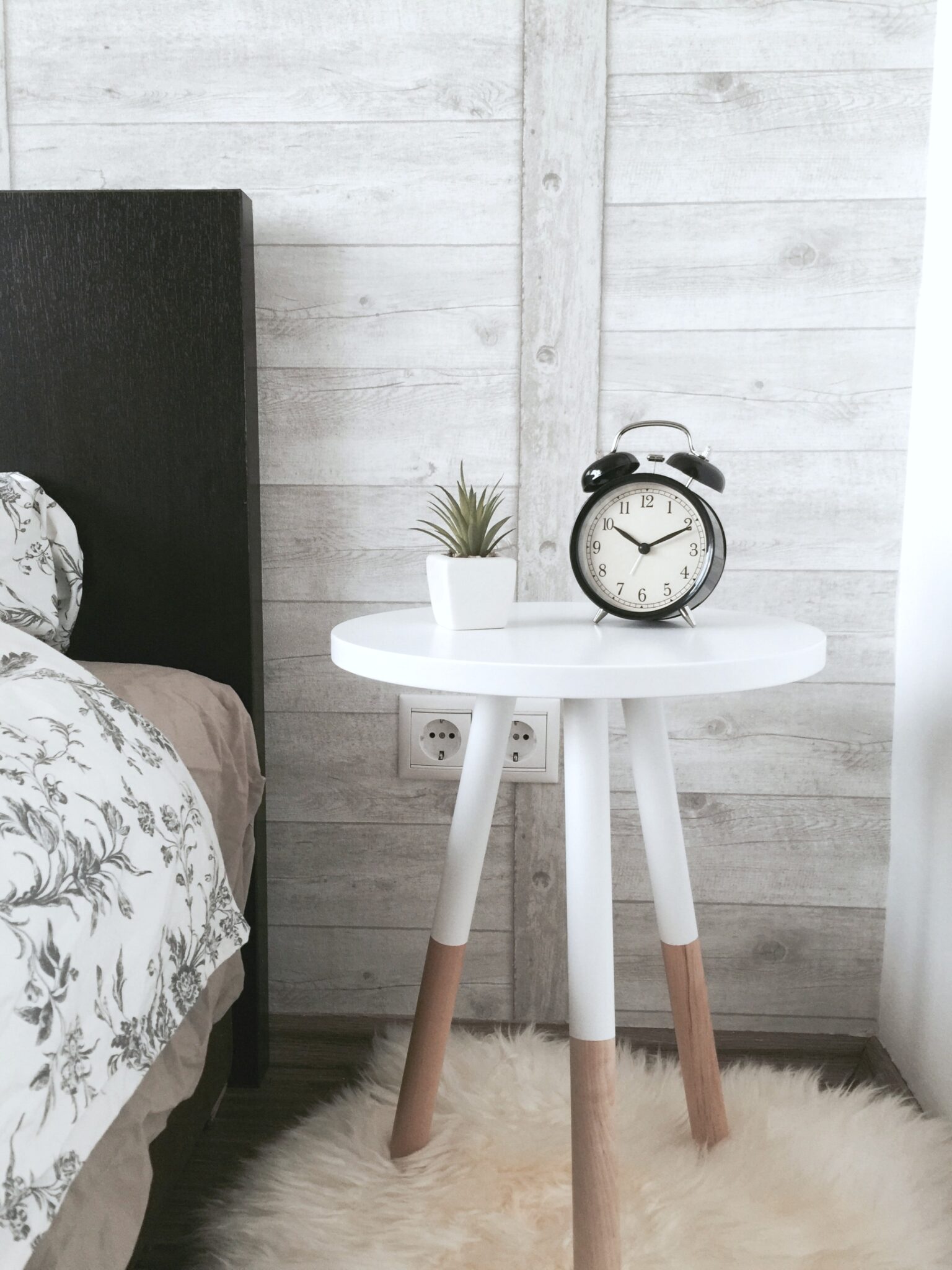 A bedroom with a nightstand and clock sit in a guest room. Find out how to create the perfect guest bedroom.