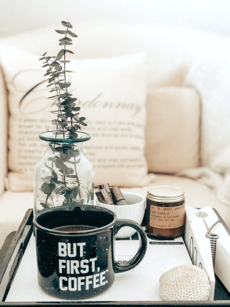 A beautiful and cozy home, a tray with a coffee mug and other creature comforts sits on the coffee table. The mug reads, "but, coffee first."