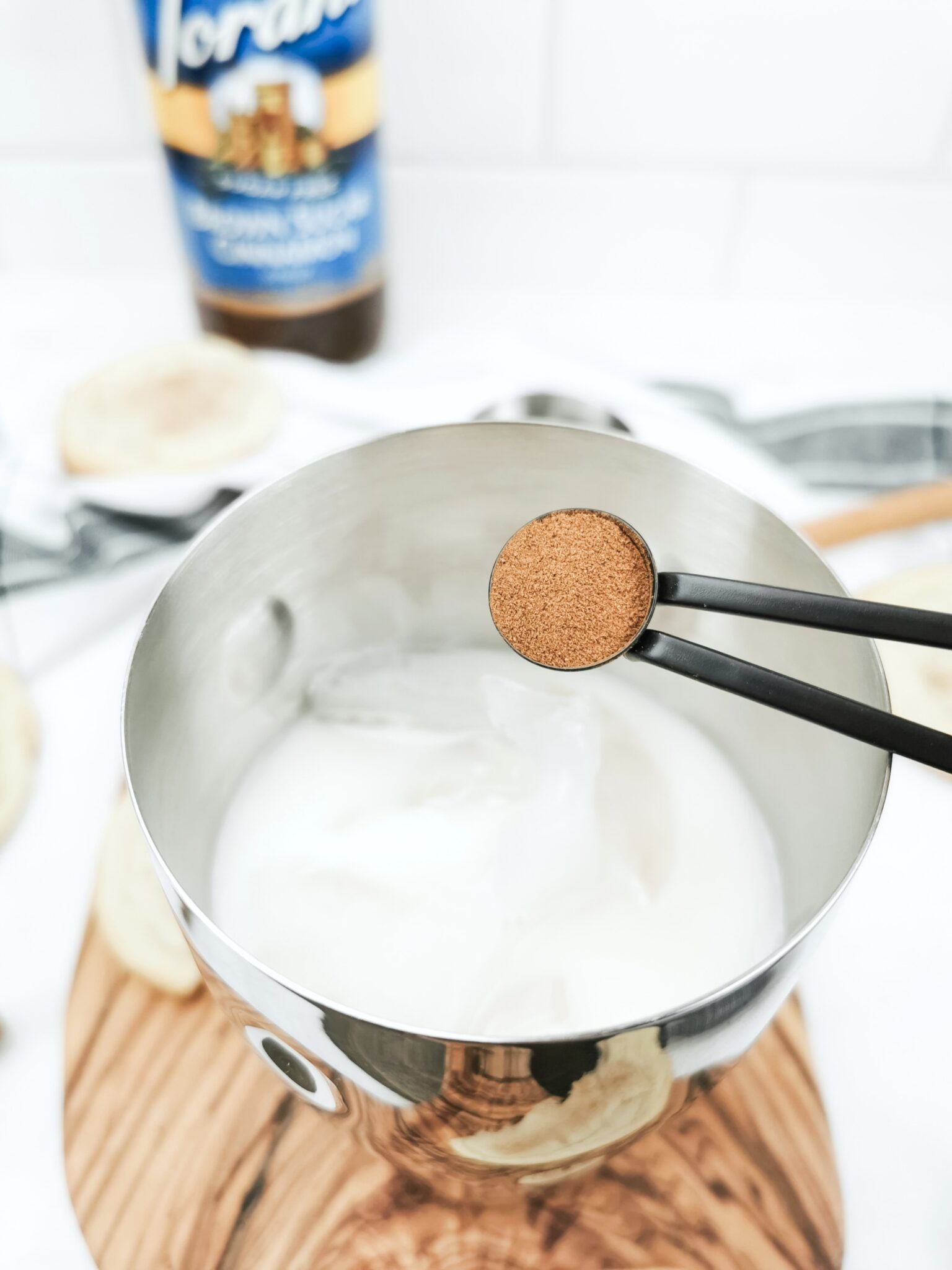 A 1/4 teaspoon of cinnamon is being poured into a drink shaker to make a Caramel Snickerdoodle Mocktail.