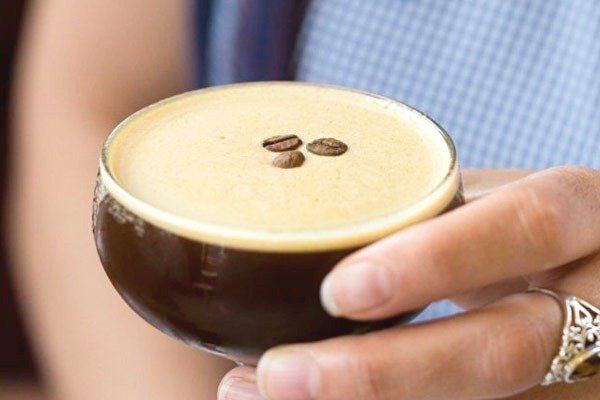 A cup of coffee topped with three coffee beans. 