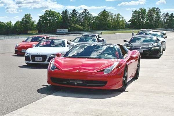 A group of super cars are parked on a race track.