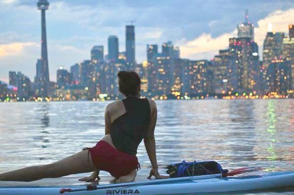 Woman on a paddle board with the Toronto skyline in the background. 