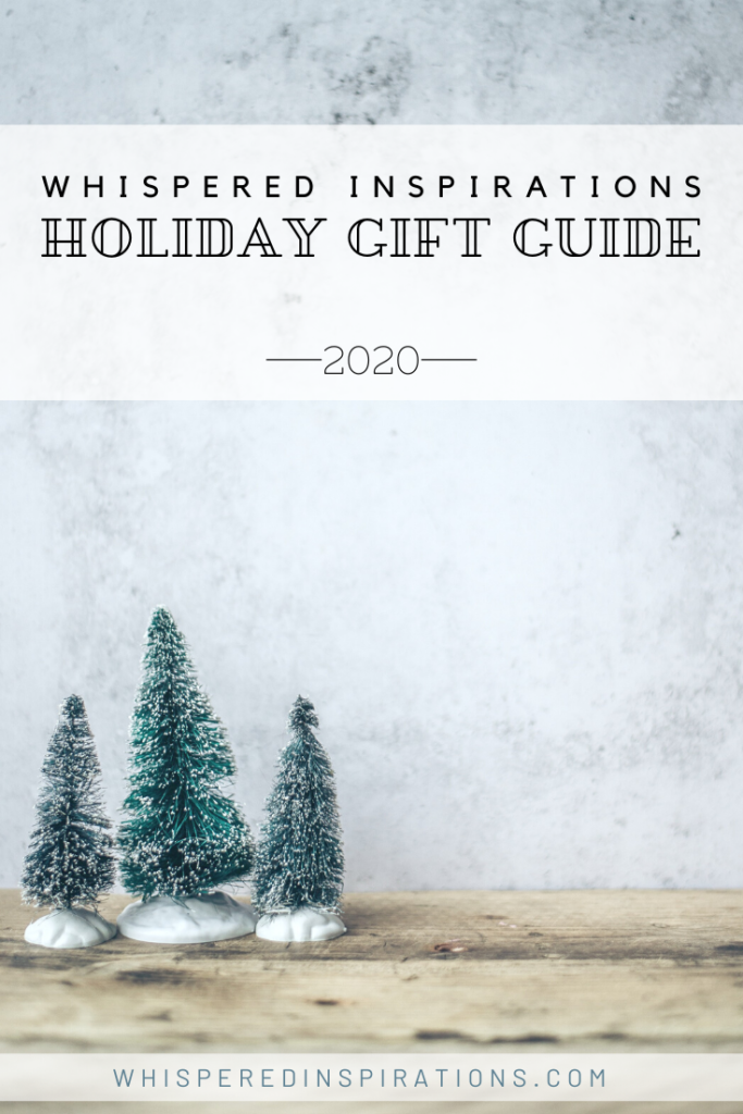 A stone background and a wooden table top. 3 little snow-covered pine tree figurines are on top of the table. A banner reads, "Whispered Inspirations, Holiday Gift Guide, 2020"