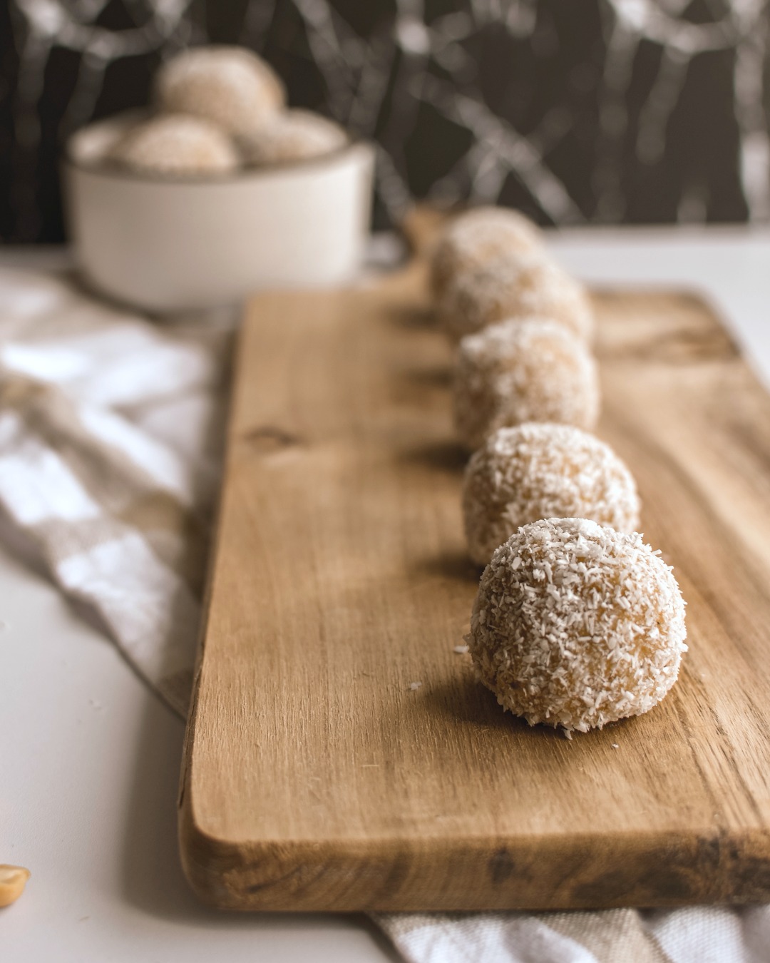 A cutting board holds a  long line of coconut peanut butter protein balls.