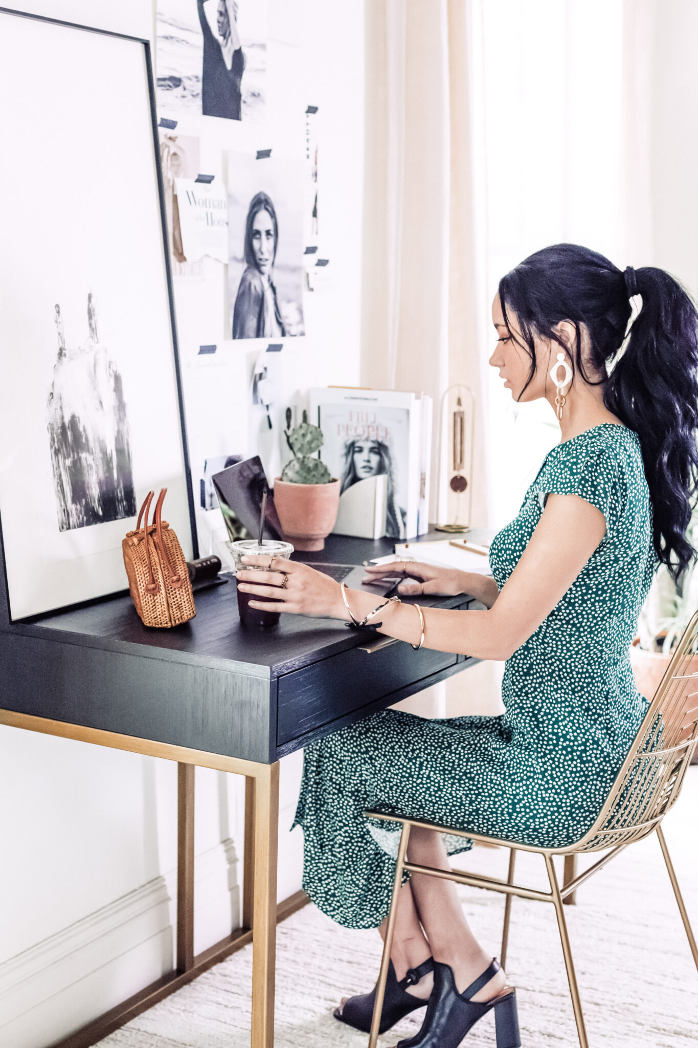 A woman sits in her home office, she wears a green desk and has her hair done. This article gives you tips for the best outfits for working from home.