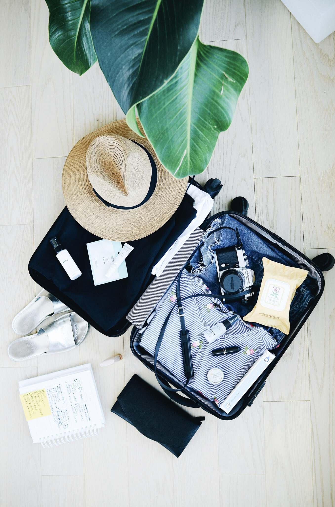 A flat lay shot of an open luggage with clothes, shoes, accessories, and more for a vacation. This articles covers packing tips and tricks for vacation.