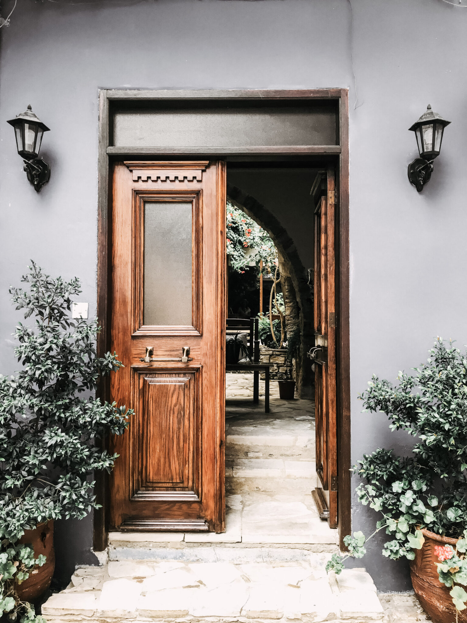 Beautiful wood door is open and the front porch is seen. This article covers 4 simple ways to overhaul the outside of your home. 