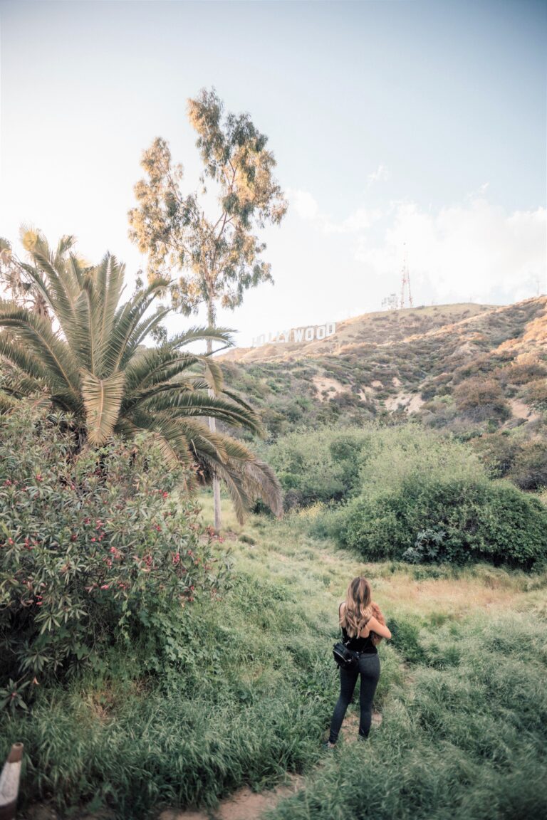 A woman is hiking towards the Hollywood sign. This article covers things to do in Los Angeles, California.