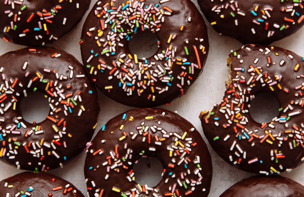 A close-up of baked chocolate-glazed donuts with sprinkles.