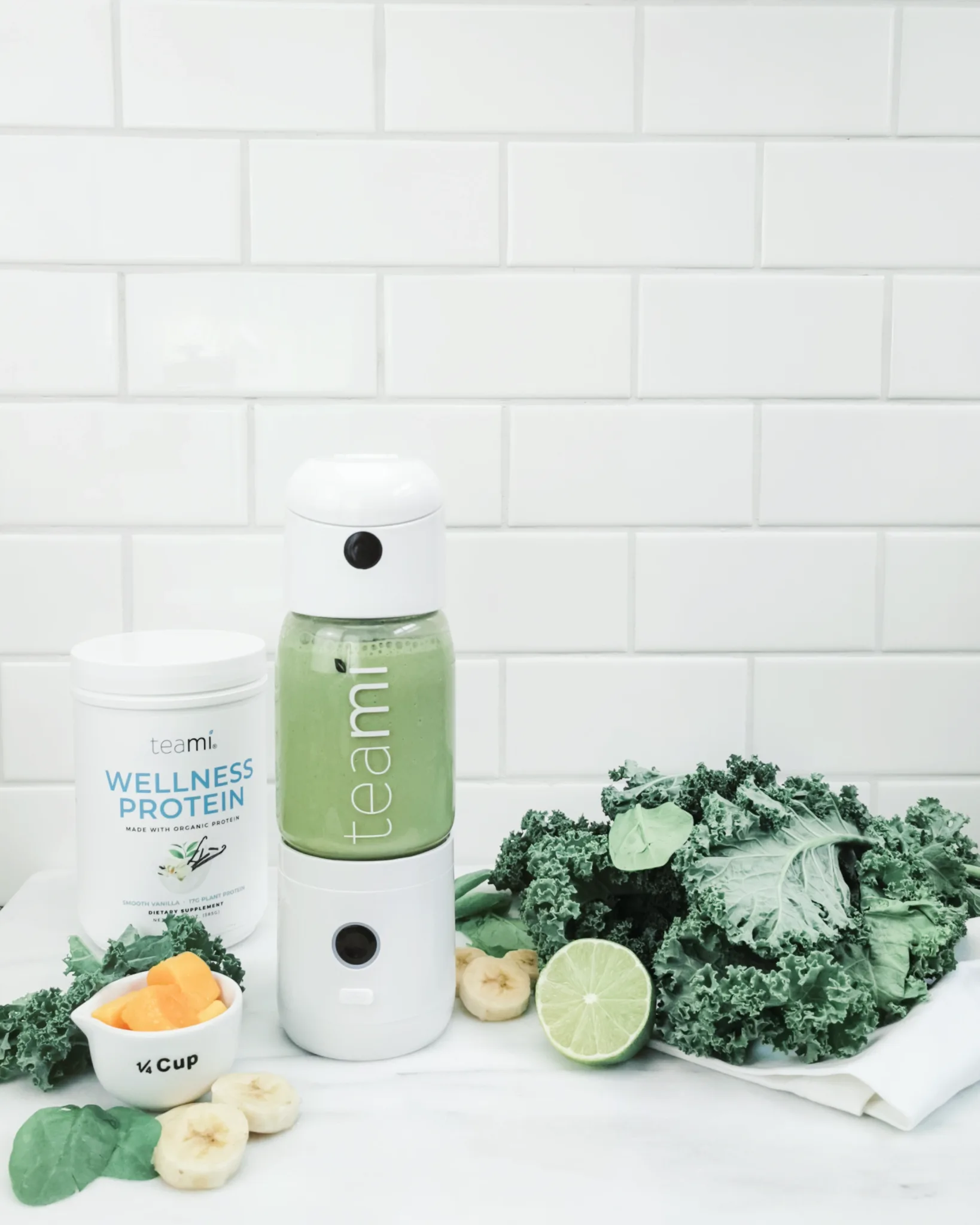 A Teami mixer is on a counter with all the ingredients needed to make a super easy Green Smoothie.