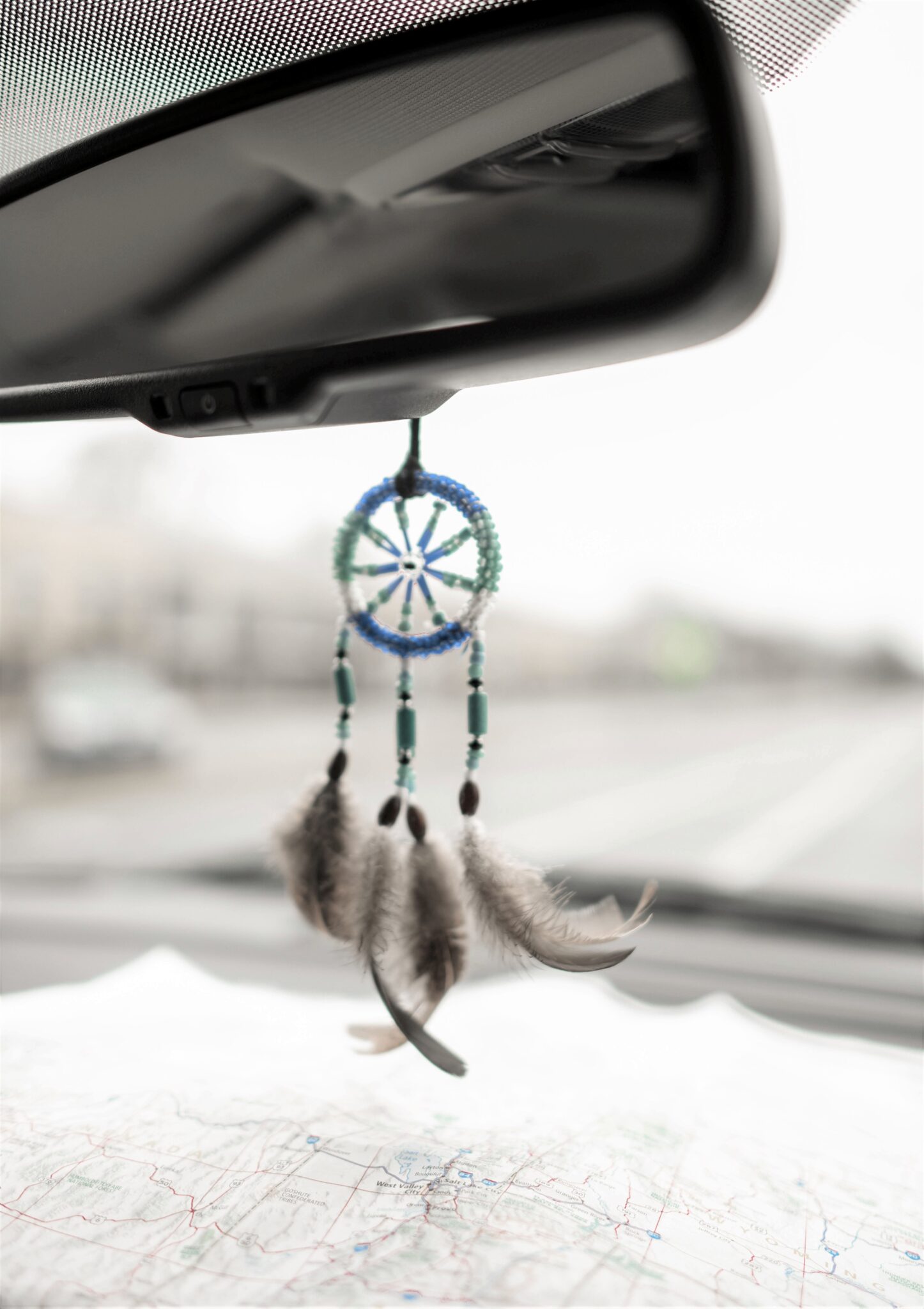 A dreamcatcher hangs on the rearview mirror and a map lies below, and ahead is the open road. This article covers what should your road trip route look like?
