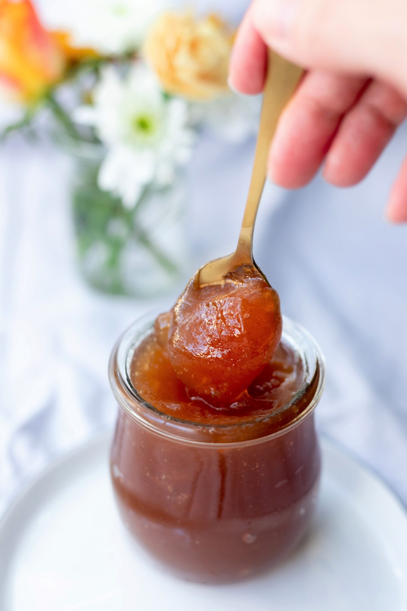 A spoon is being taken out of a glass container of jam.  This article covers knowing the difference between jellies and jams. 