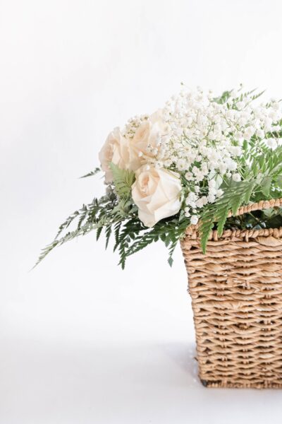 A half view of a basket with a white bouquet of flowers in it. It's against a white background. This article covers 5 reasons why you should give flowers as a gift.