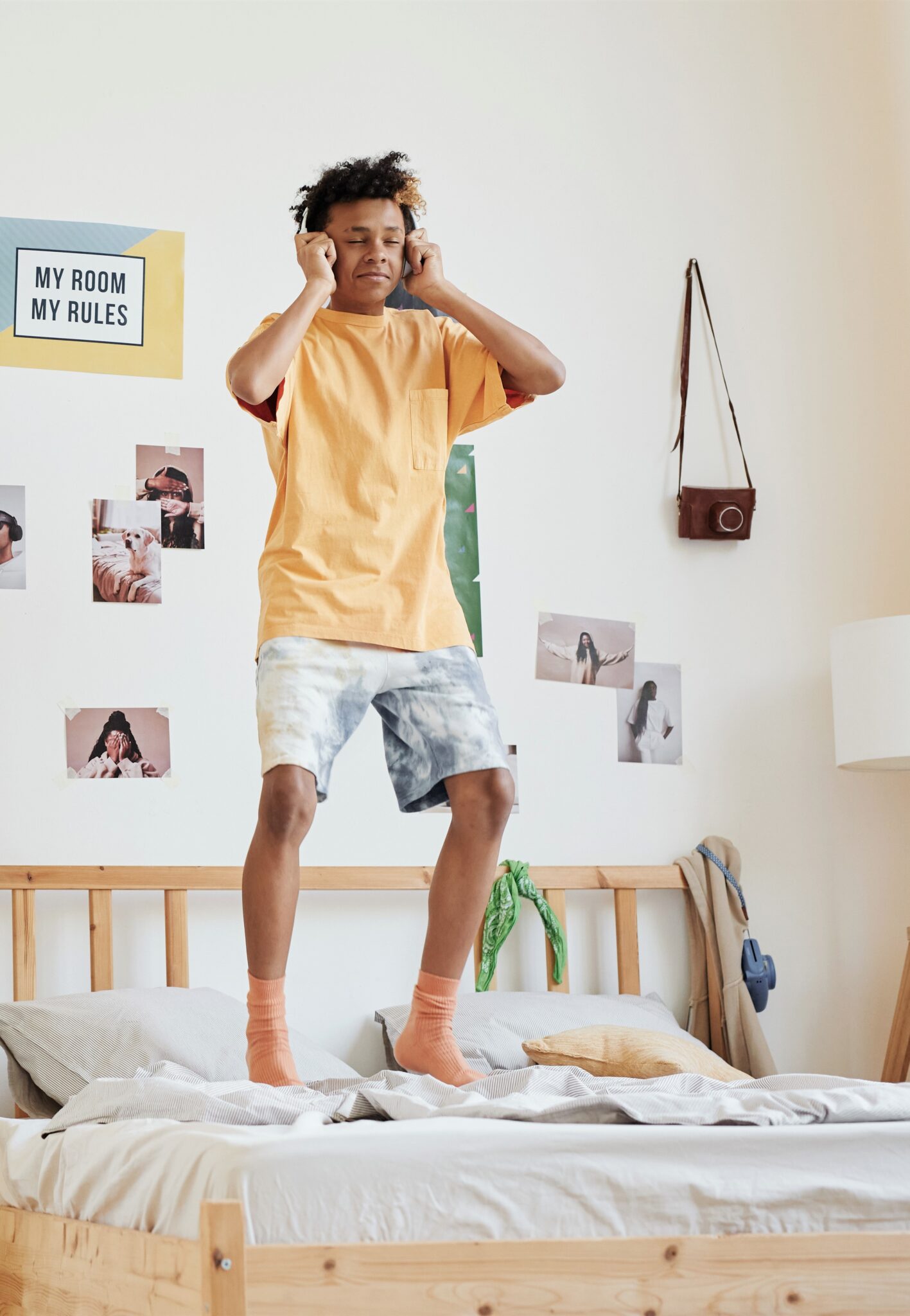 A teenager jumps on his bed. This article covers bedroom essentials for teenagers.