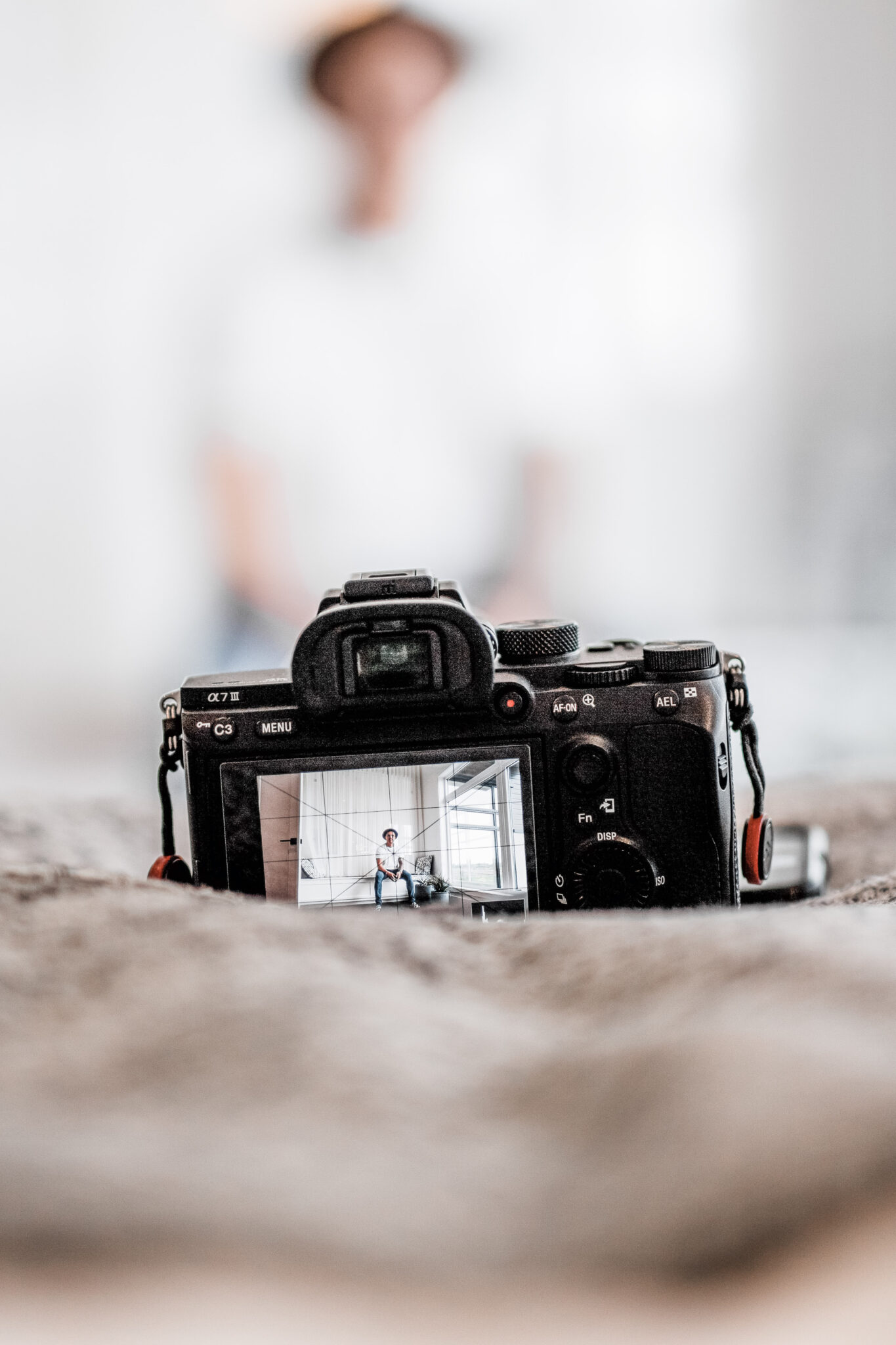 A man sets up his DSLR camera on a bed to record a vlog. This article covers professional travel vlogger secrets you need to know.