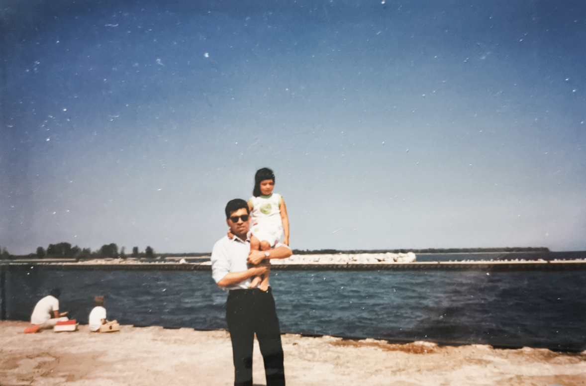 Francisco, Nancy's father, hold her on his shoulder at the beach.