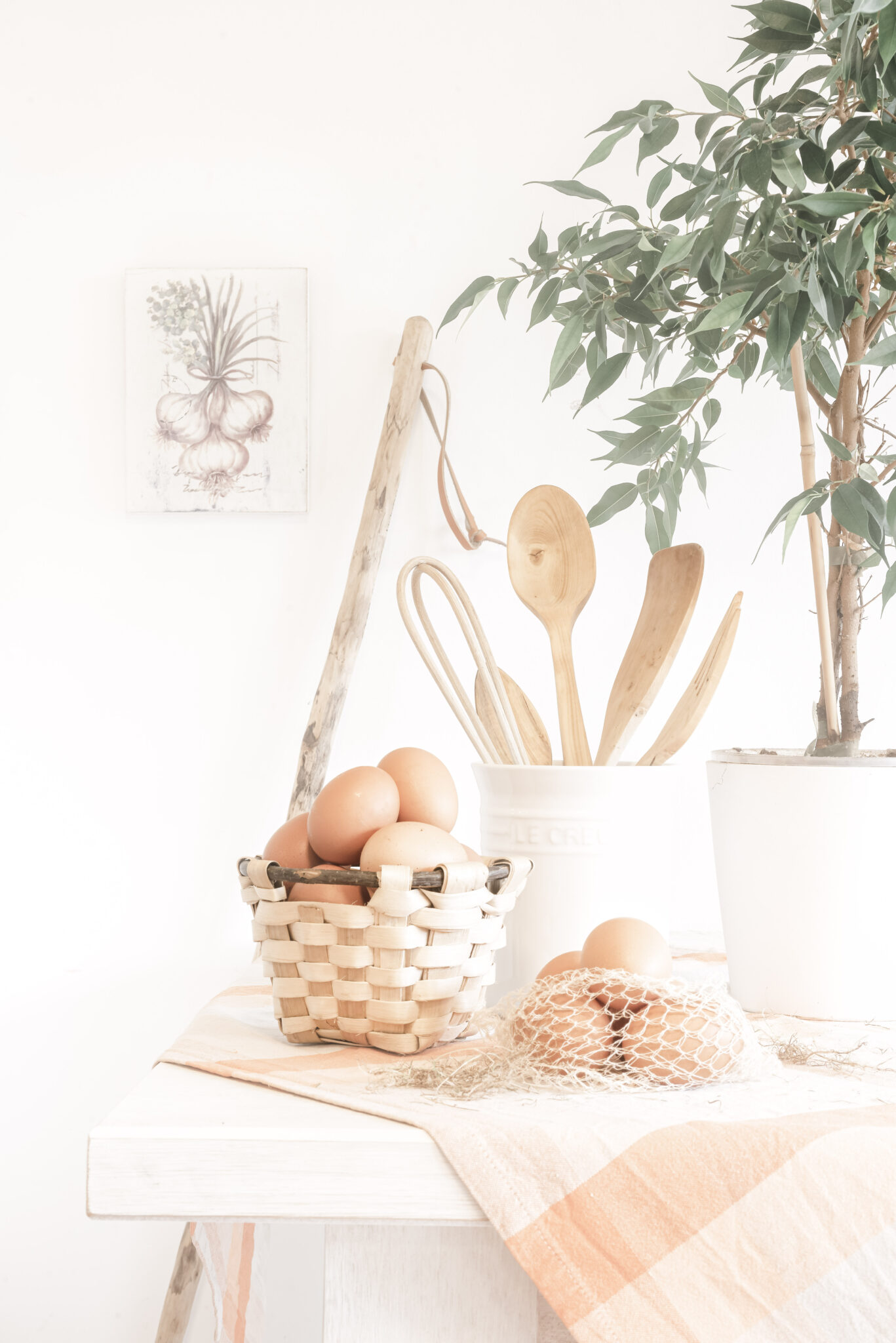 A farmhouse style kitchen shows a basket of brown eggs and a container of kitchen utensils. This article covers creative ways to organize your kitchen utensils. 