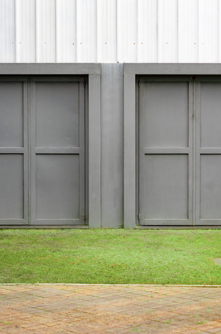 A grey and white garage with double doors. This article covers helpful garage organization ideas you'll regret not trying.
