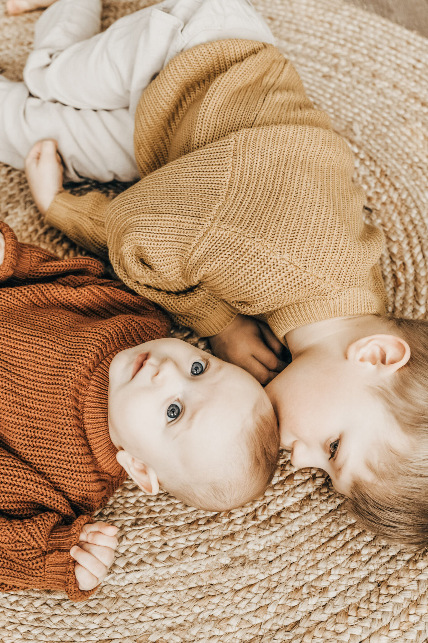 A toddler boy lay son a rattan rug with his newborn sibling. This article covers staying fit when you have a newborn or toddler. 