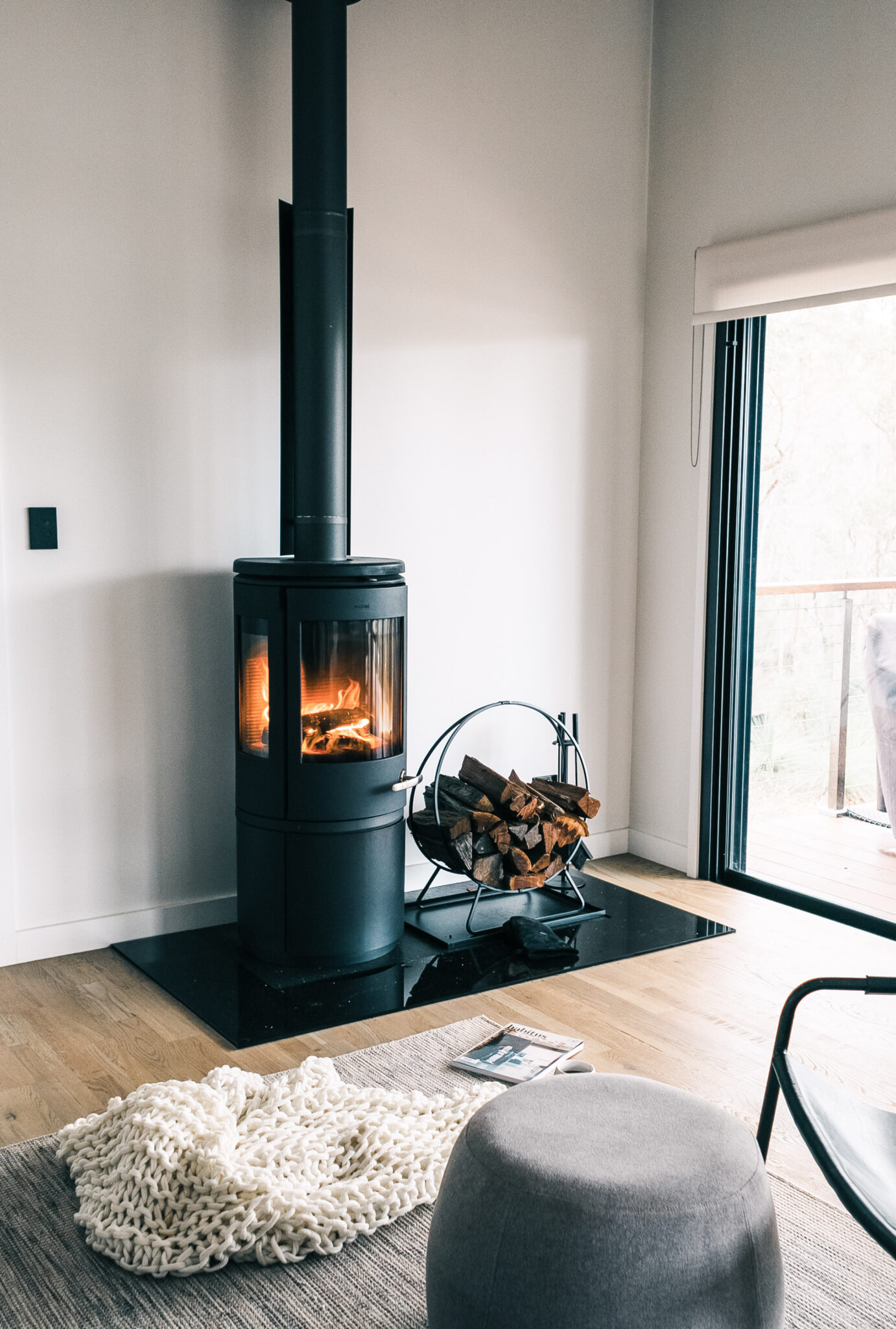 A beautiful living room is shown, it's cozy with a fireplace and plenty of blankets and a rug. This article covers 3 cost-effective ways to combat the cold this winter.