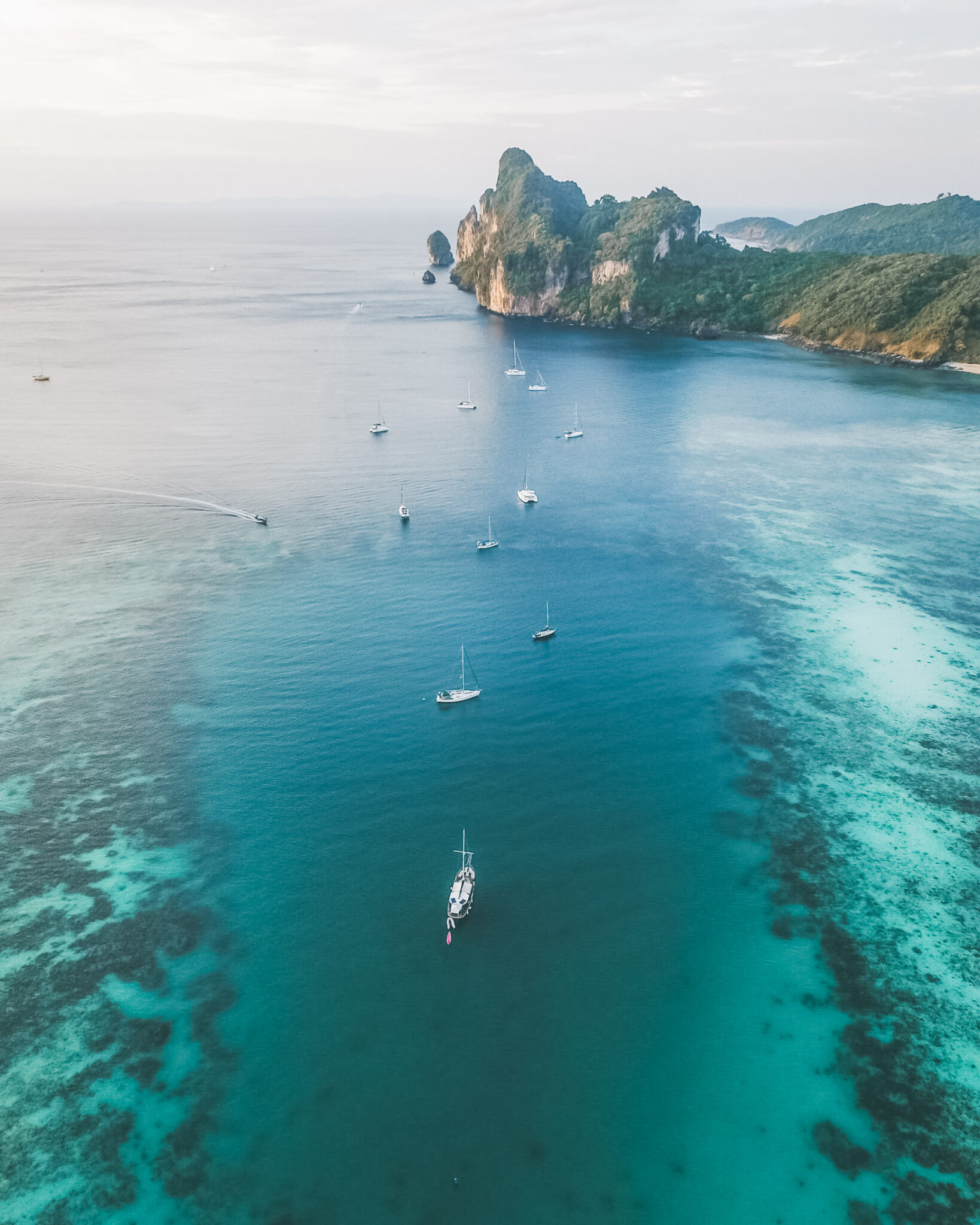 Boats are shown all across the clear waters of Phi Phi Islands in Thailand. This article covers family-friendly things to do in Thailand.