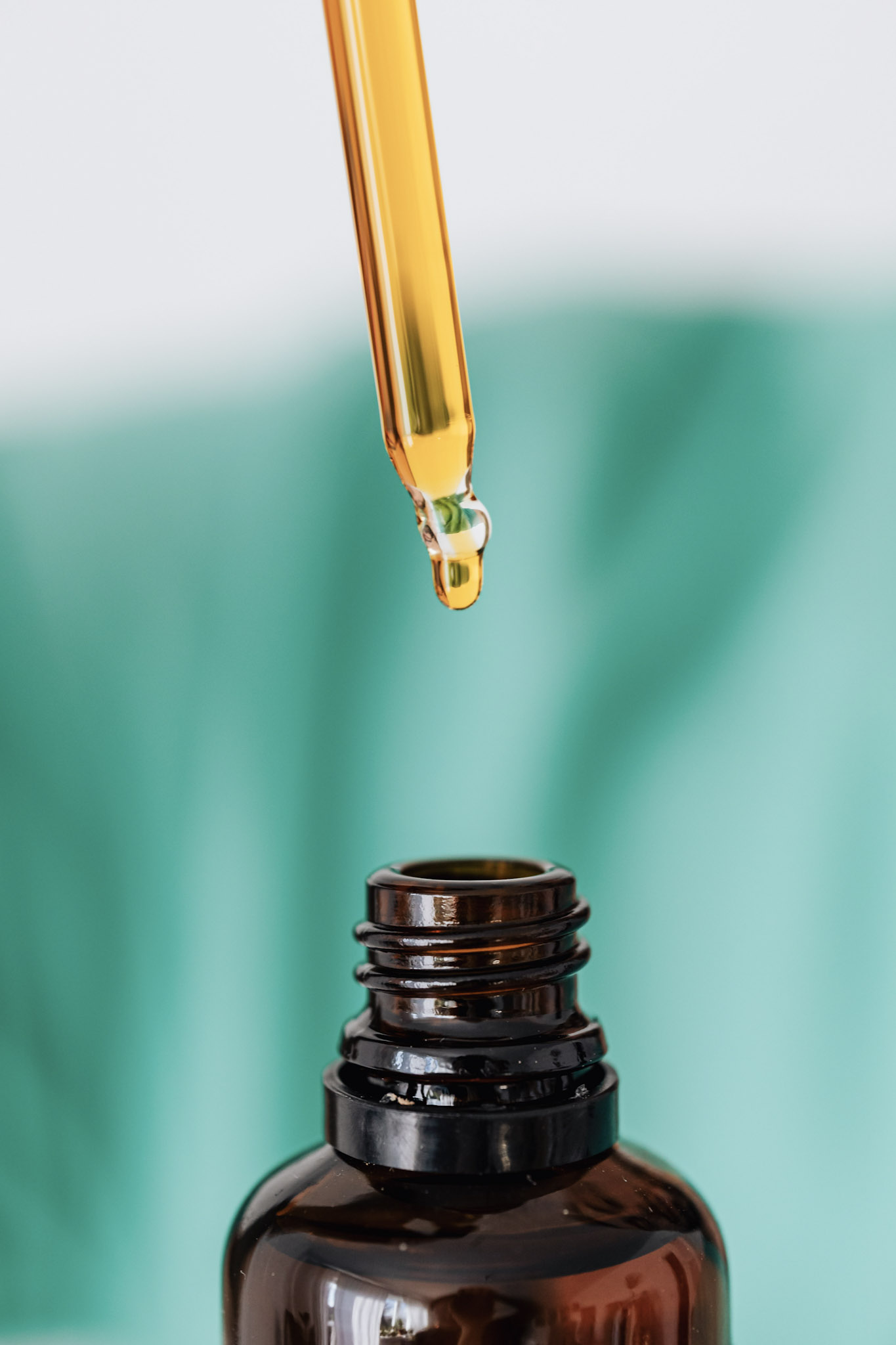 A dropper is above an open bottle, a drop of CBD oil drips down. This article covers the benefits and risks of cannabidiol.