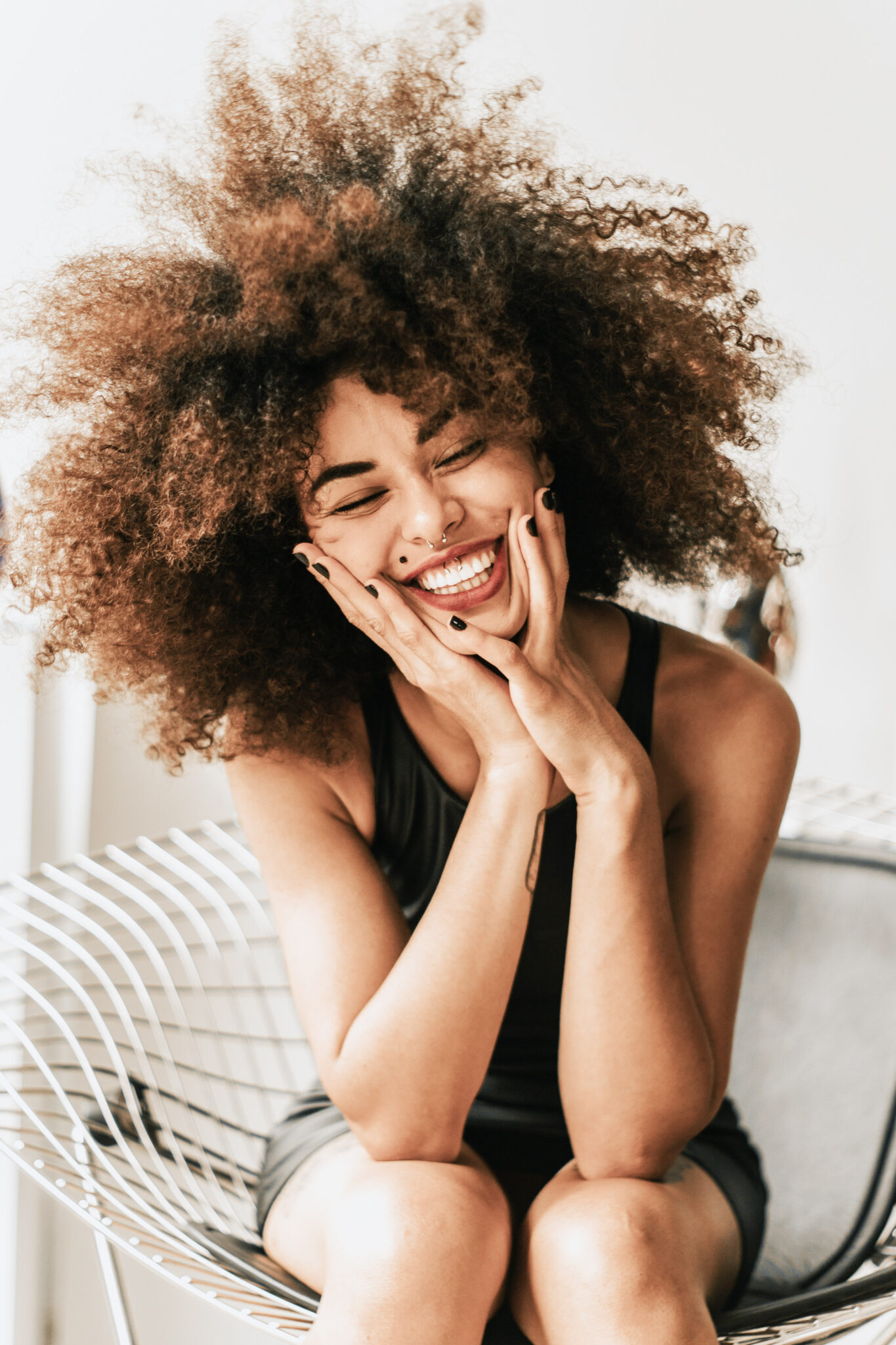 Woman holds her face and smiles, she looks confident, and carefree. This article covers the best tips for living life with more confidence.