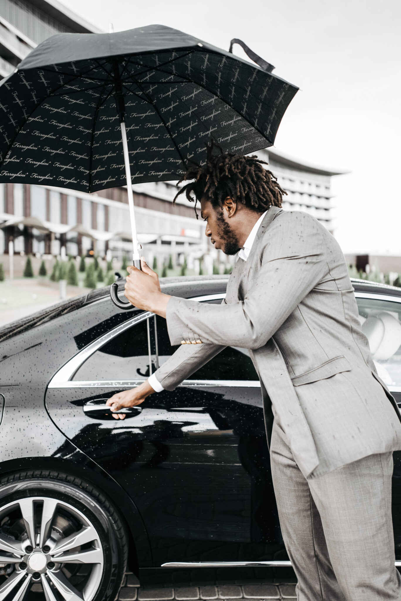 Driver holds umbrella and opens the door to a private car. This article covers why hiring a private driver eliminates stress.