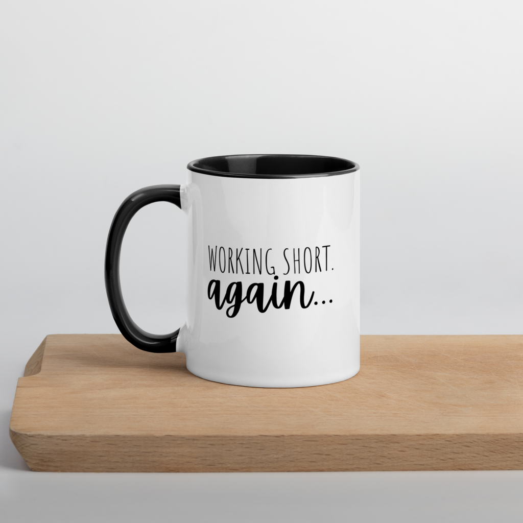A white mug that says, "Working Short Again' is shown. It's an item from Whispered Inspirations Etsy Shop. 