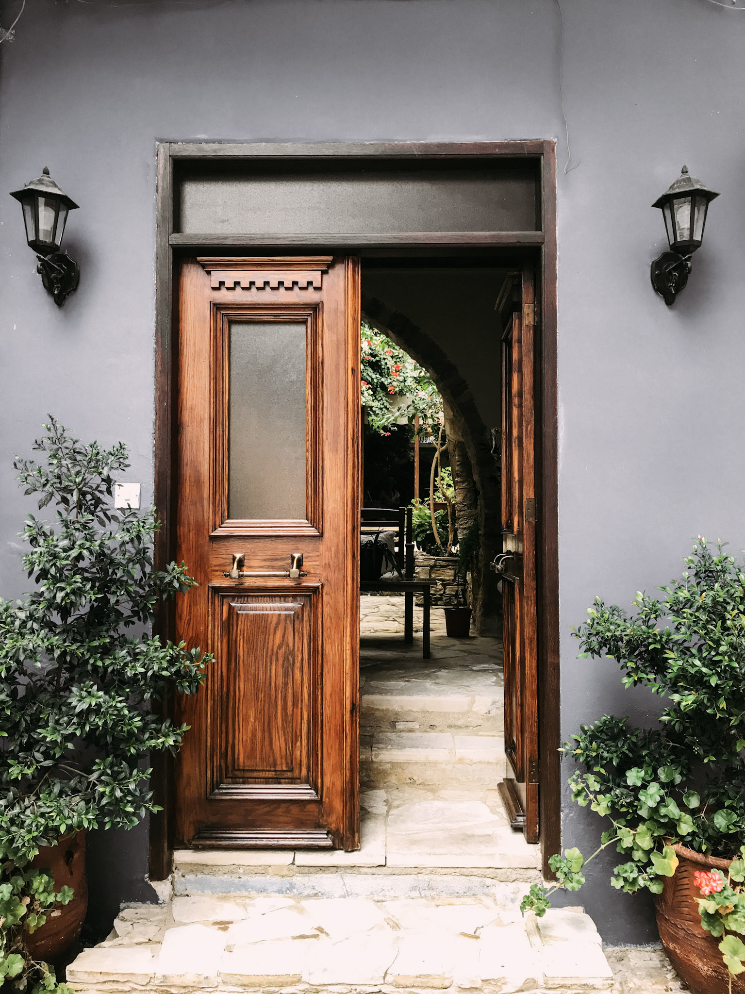 A beautiful grey home with a gorgeous wooden door is shown. It leads to a terrace. This article covers ways to improve home access points.