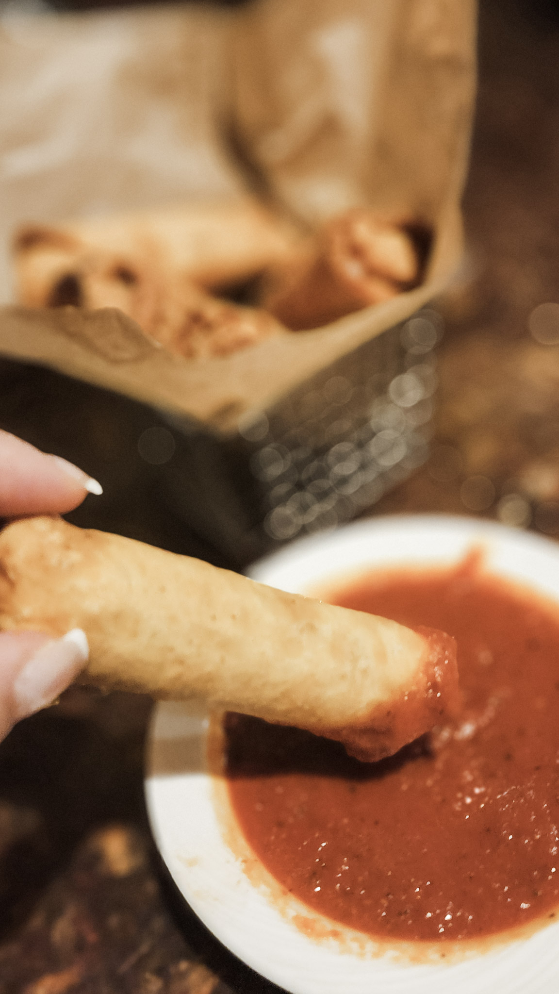 A pizza roll being dipped into marinara sauce. An appetizer available at Three Sisters.