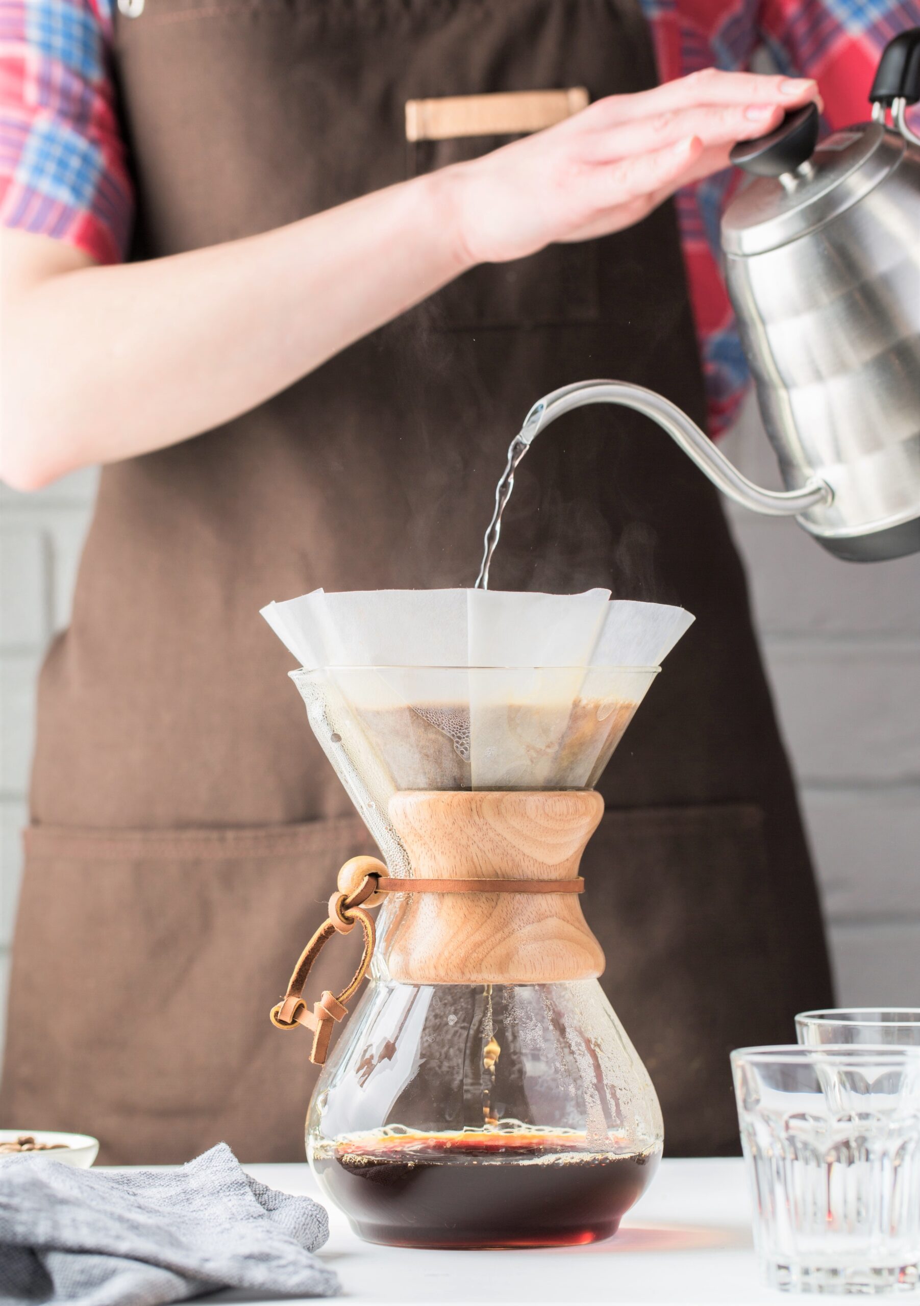 Woman pours water over coffee in filter. This article covers how single-origin coffee and how it differs from blends and mass produced coffees.