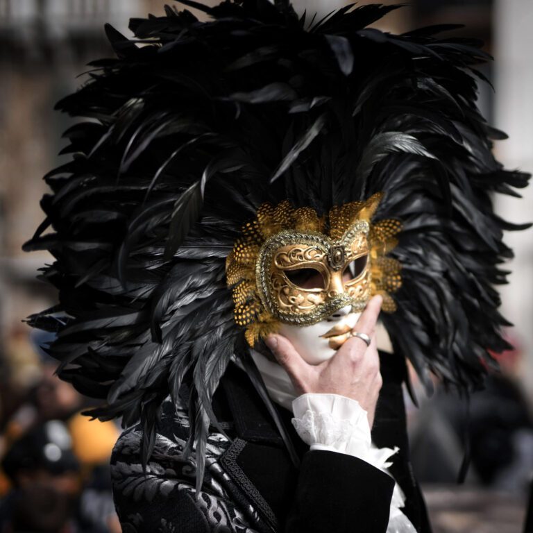 A man wearing a gold mask with black feathers for Mardi Gras.