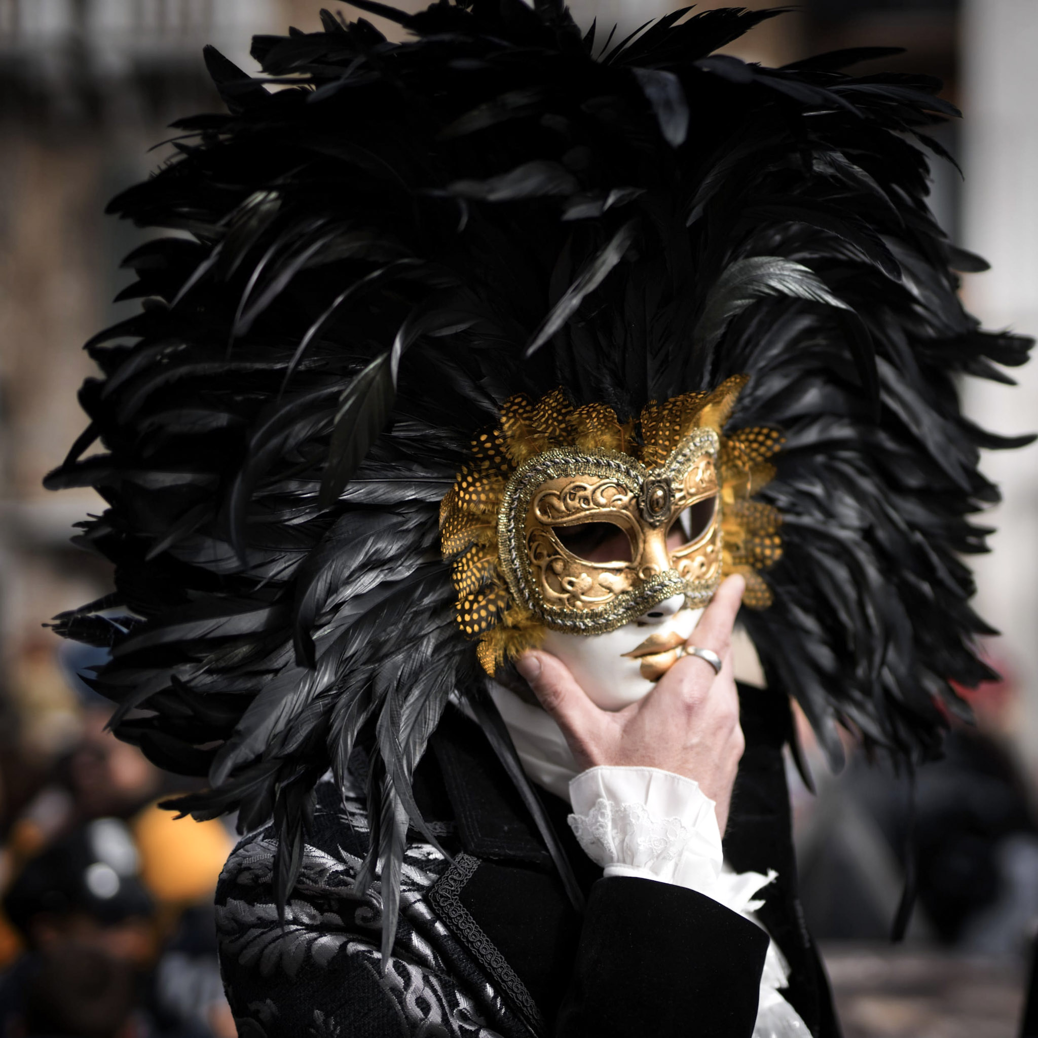 A man wearing a gold mask with black feathers for Mardi Gras. This article covers cultural festivals you should visit in your lifetime.