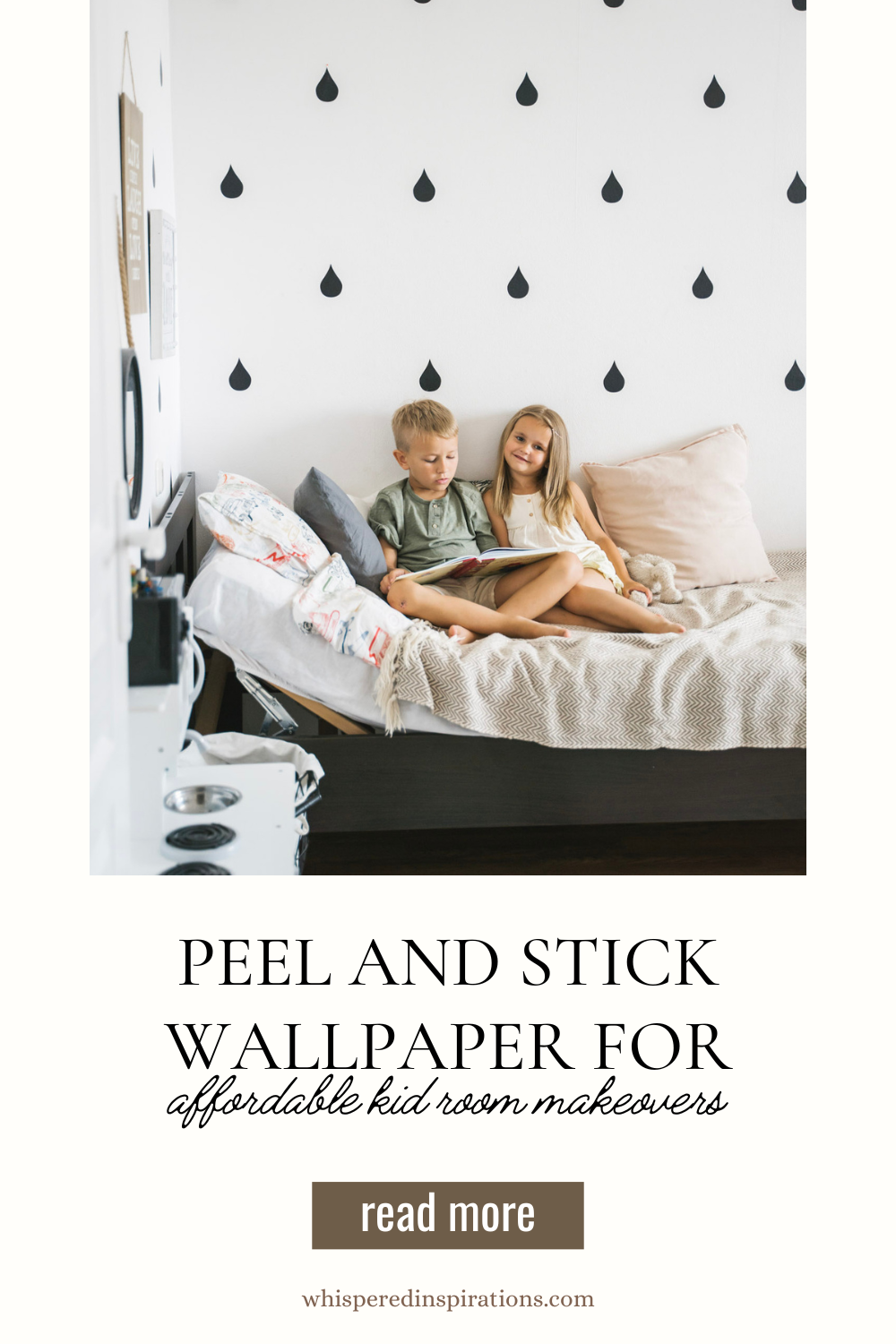 A boy and a girl read a book together on a bed. Behind them is a black and white peel and stick wallpaper. 