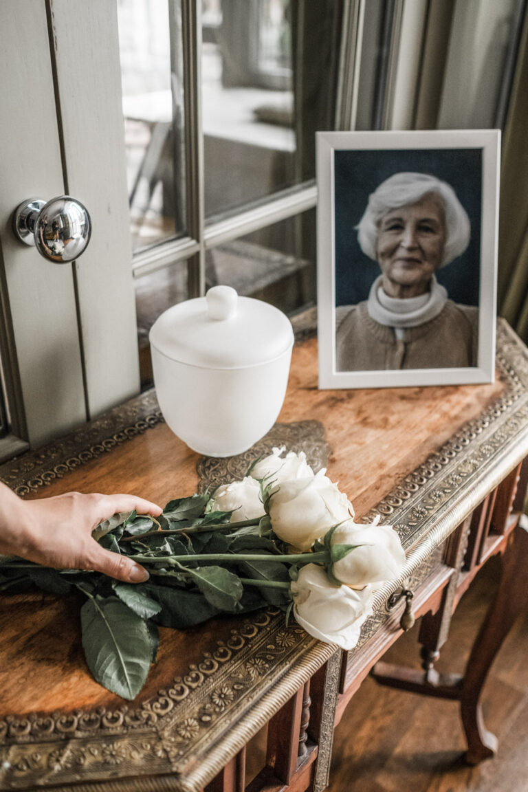 A picture frame of an elderly woman is shown and her ashes are next to her on a table. Someone places flowers there. This article covers beautiful things to do with your loved one's ashes.