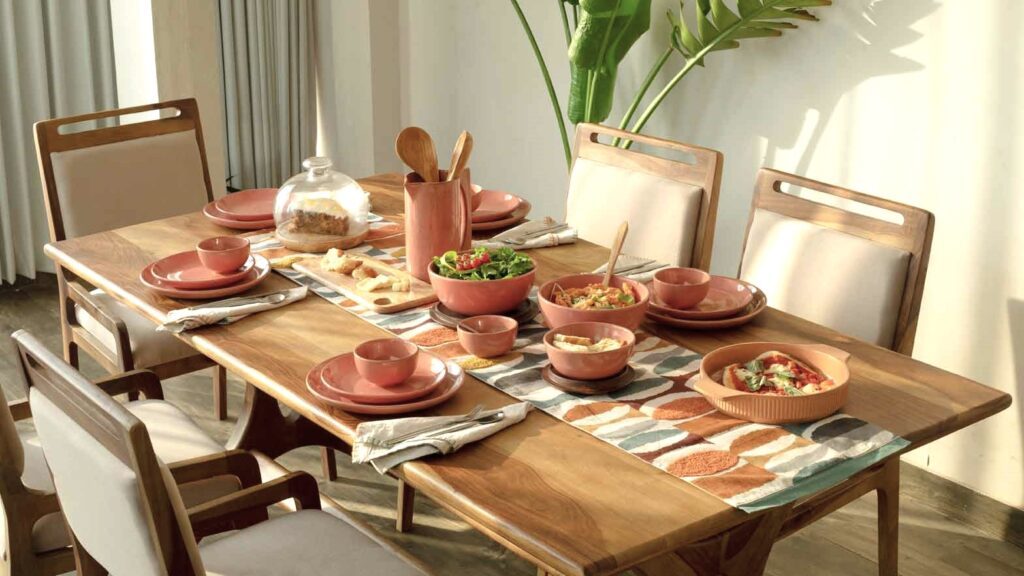 A wooden table with rose colored dishes. They're set up for dinner. This article covers how to style photos for modern living spaces.