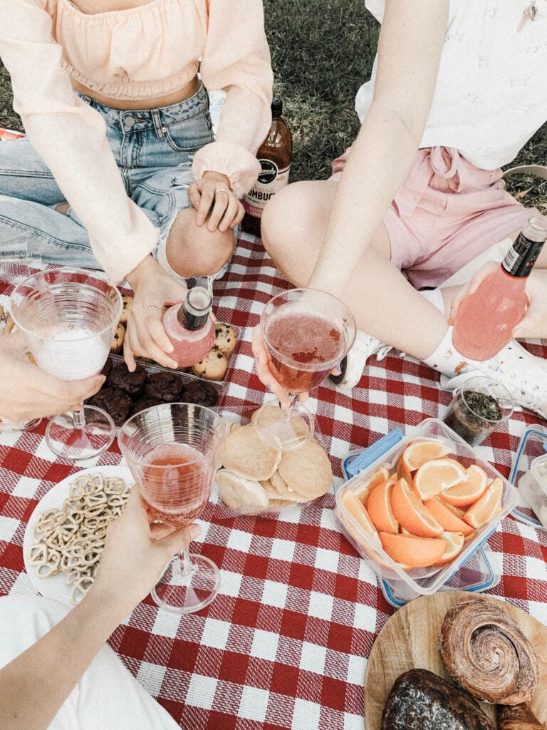 A group of women set up a picnic with lights snacks and fruits. This article covers snacks for outdoor picnics.