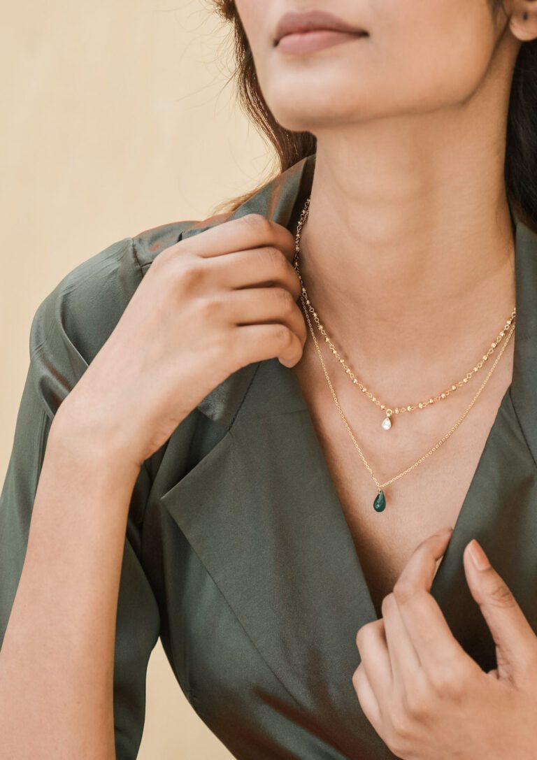 A woman holds her hand by her neck and shows off necklaces. This article covers maximizing the value of your jewelry collection.