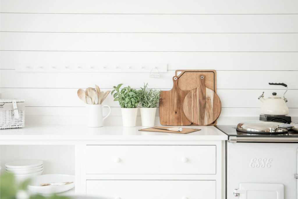 A beautiful vintage white kitchen with plants and brown cutting boards. This article covers finding zen in the heart of the home and the calming effect of kitchen hues.