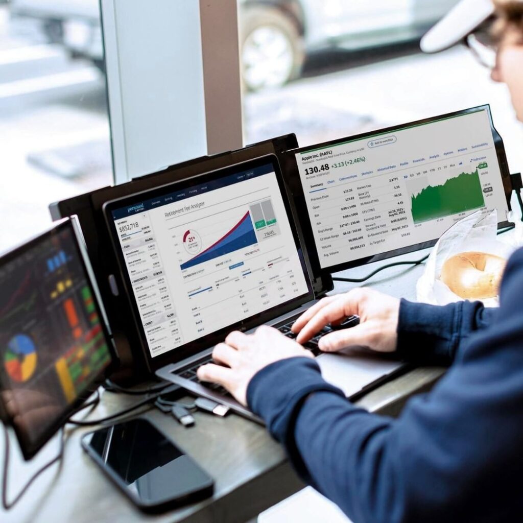 Two portable monitors are shown with a laptop. This article covers portable monitors, and health ergonomics, and eye strain.