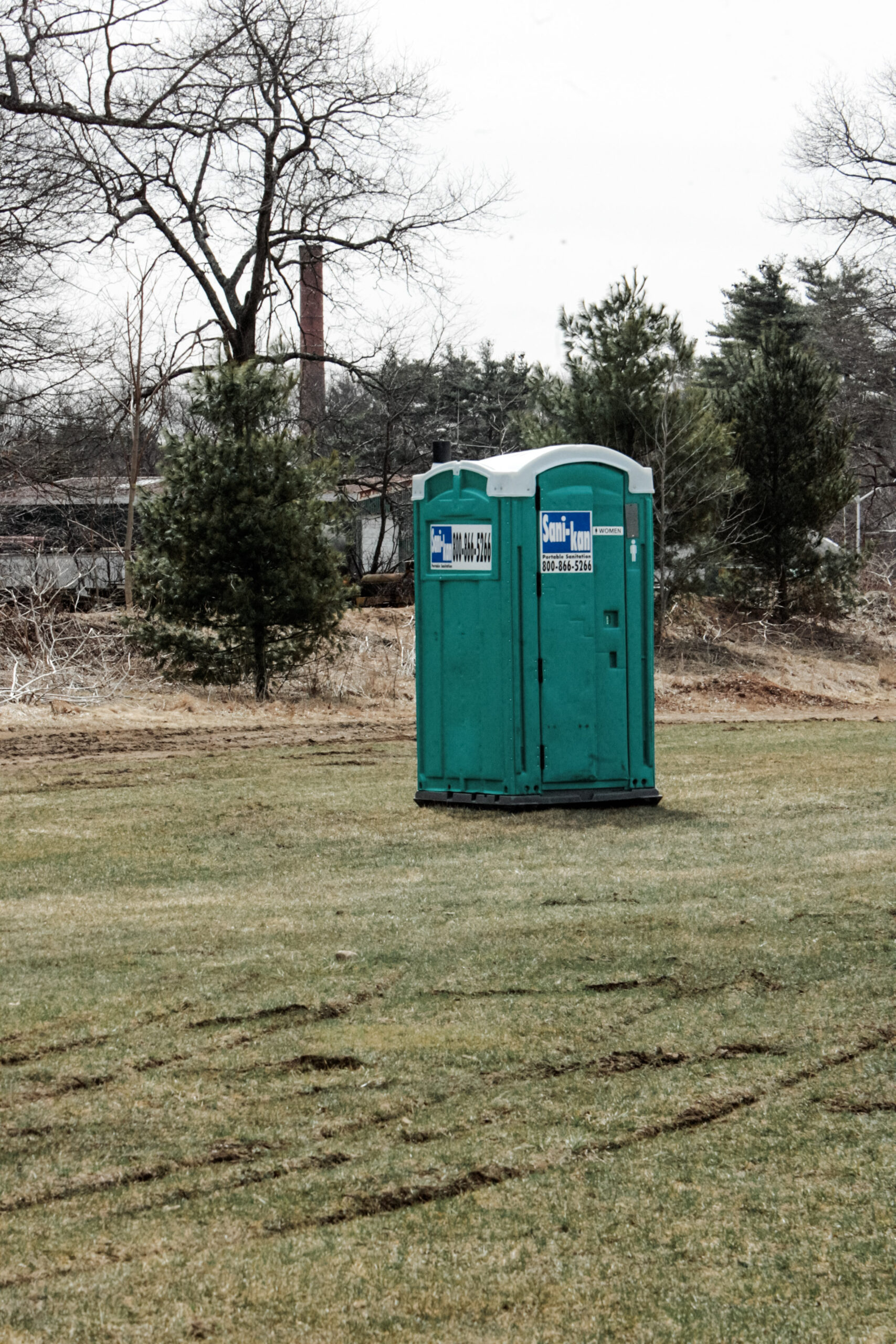 A porta potty sits in a field of an event. This article covers tips for choosing the right porta potty for your event.
