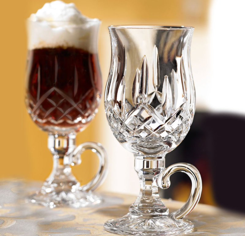 A fancy Waterford cup is filled with a drink while one remains empty to show it's beauty.
