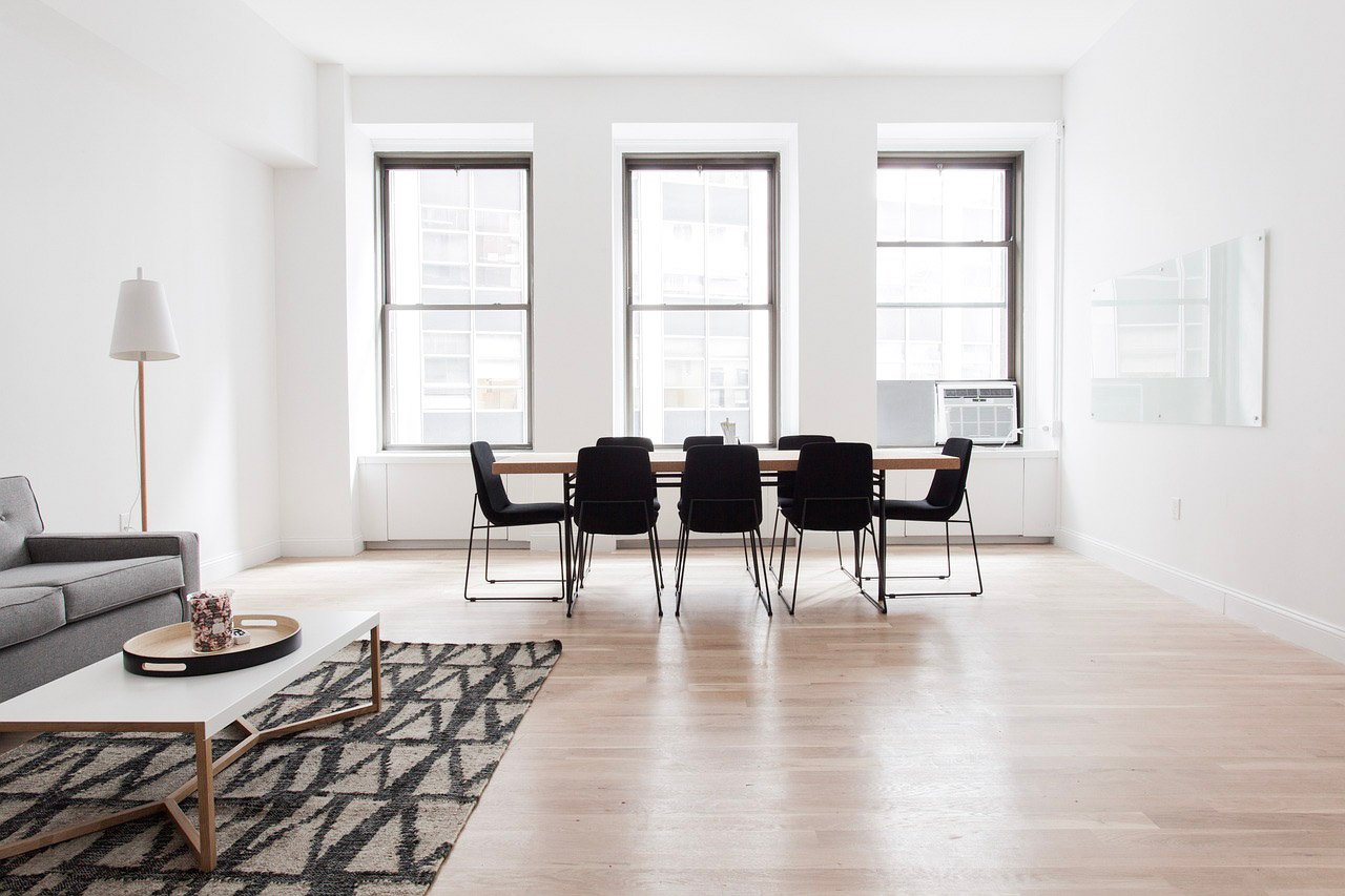 A beautiful open space with a large table, couches, and bright windows. This article covers how to increase energy efficiency for your home.