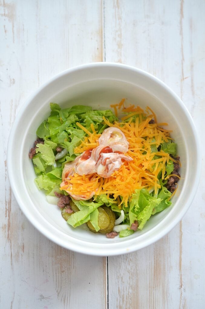 Dressing being added to the Big Mac in a Bowl.