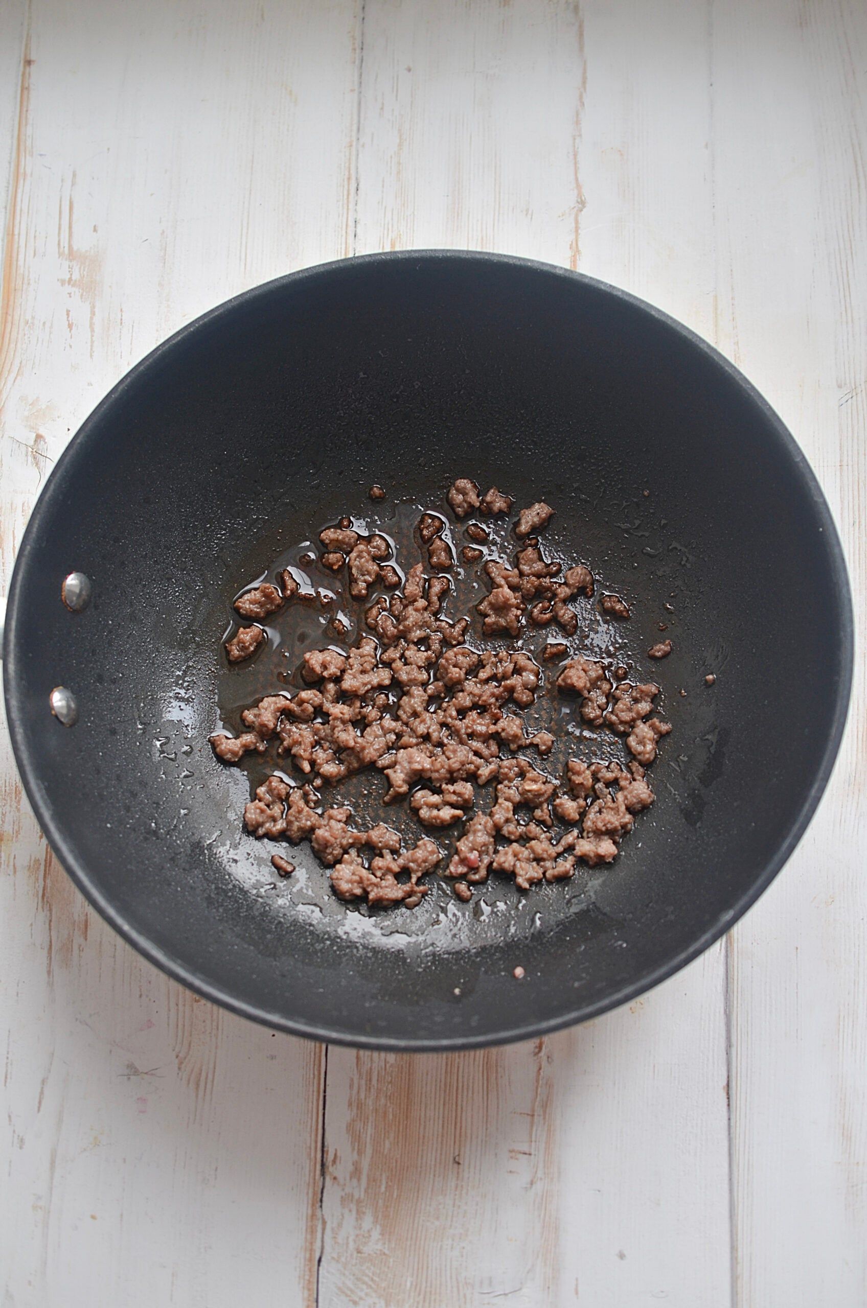 A frying pan with ground beef cooking.