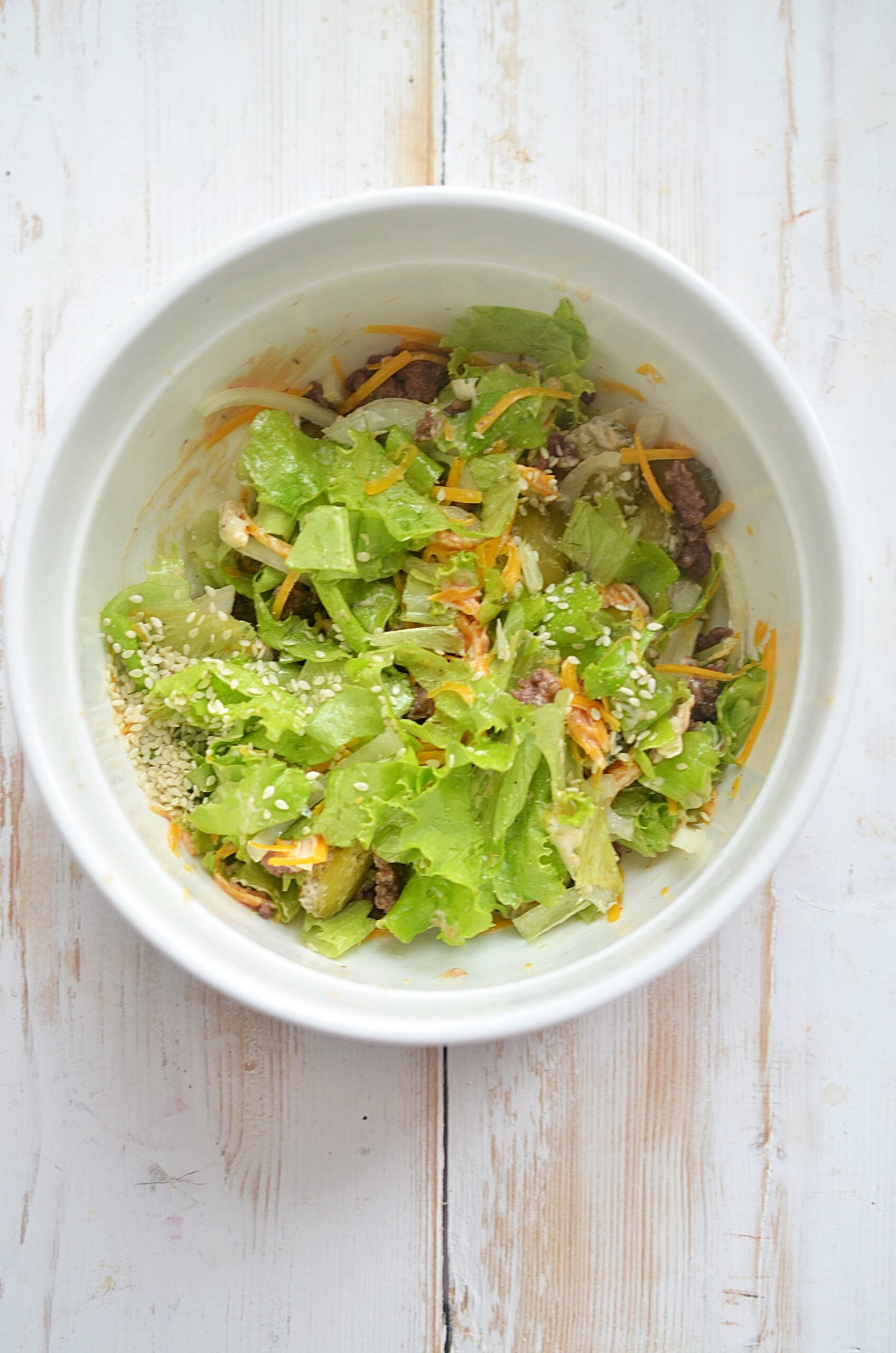 Adding sesame seeds and dressing to be mixed.
